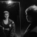Black and white photo of woman with short hair reflecting in mirror, creating a contemplative mood.